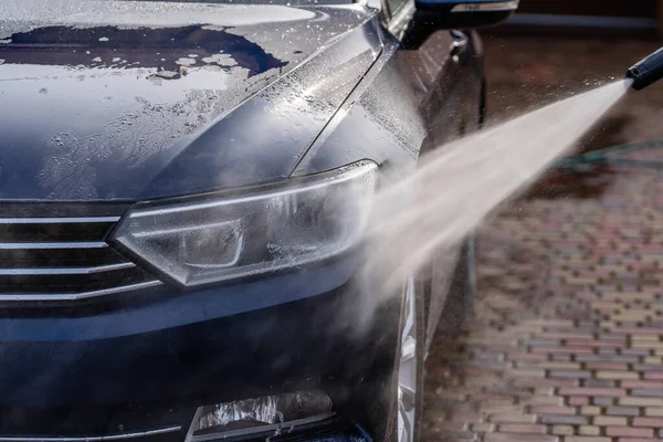 用高压水清洁剂清洗一辆蓝色轿车 — 图库照片