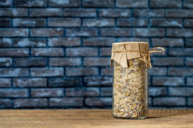 Deniz Himalaya tuzu, kuru lavanta ve papatya çiçekleri ahşap bir masada, tuğla duvar zeminli cam bir kavanozda, kapatın, boşluğu kopyalayın