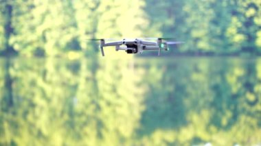 Kiev, Ukrayna - 01 Ekim 2021: DJI Maviç Air 2S İHA 'sı, bir önceki Maviç modeline göre büyük bir güncelleme yaparak, arka planda asılı duruyor. DJI Mavic Air 2S İHA 'sı orman gölünde uçuyor.