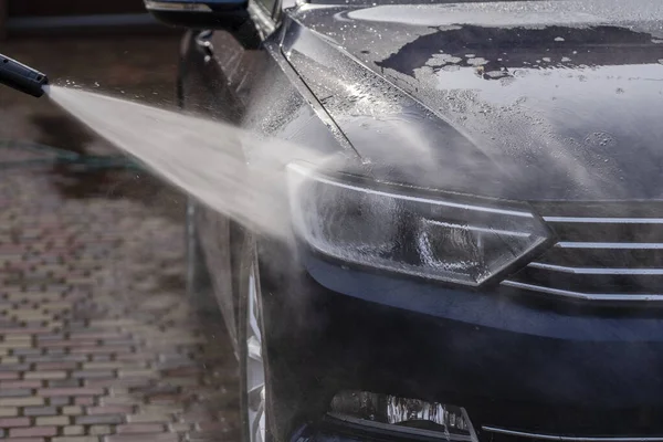 用高压水清洁剂清洗一辆蓝色轿车 — 图库照片