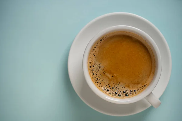青を背景にソーサー付きの白い磁器コーヒーカップ トップビュー コピースペース クローズアップ 朝食にホットコーヒー — ストック写真