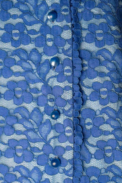 Detail of a blue women blouse made of guipure fabric with mother-of-pearl buttons, close up