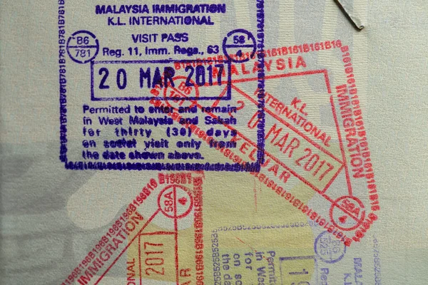 Inside page of a traveled Ukrainian passport with stamps from customs of Malaysia. Border stamp in the passport when crossing the state border Malaysia, close up. Vacation and travel concept
