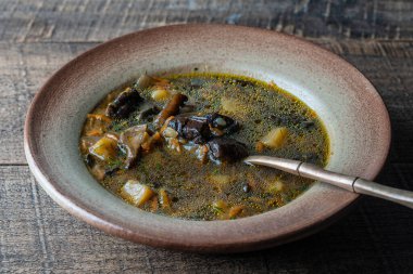 Porcini mantarlı mantar çorbası tabağı, patates, havuç, soğan, siyah arka planda taze yeşil dereotu ve biber, kapatın.