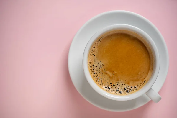 ピンクの背景にソーサー付きの白い磁器コーヒーカップ トップビュー コピースペース クローズアップ 朝食にホットコーヒー — ストック写真