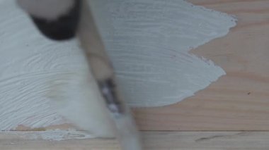 Yakından fırça kullanarak beyaz boyayla çam ağacını boyamak. Yağlı boyalı ahşap yüzey boyası, yenileme konsepti