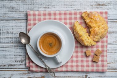 Ahşap bir masanın üzerinde çay tabağı ve limon kurabiyeli beyaz porselen kahve fincanı, yakın çekim, üst manzara. Kahvaltıda sıcak kahve.