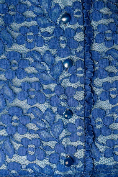 Detail of a blue women blouse made of guipure fabric with mother-of-pearl buttons, close up
