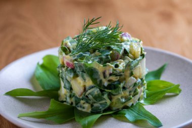 Sağlıklı yeşil pırasa salatası, haşlanmış yumurta, salatalık, turp, haşlanmış patates ve ekşi krema tabakta, yakın çekim. Haşlanmış yumurtalı yabani sarımsaklı salata.