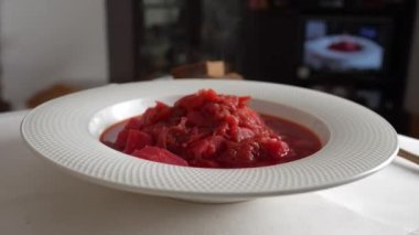 Geleneksel Ukrayna kırmızı çorbası veya kırmızı pancar, patates, havuç, lahana, beyaz kasede fasulye, yakın çekim. Bir tabak kırmızı pancar çorbası çorbası masada döner. Geleneksel Ukrayna yemekleri