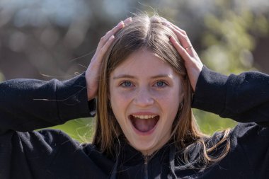 Güzel mutlu bir kızın portresi. Sarı saçlı ve çilli. Kameraya bakıyor ve büyüleyici bir şekilde gülümsüyor.