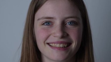 Güzel mutlu bir kızın portresi. Sarı saçlı ve çilli. Kameraya bakıyor ve büyüleyici bir şekilde gülümsüyor.