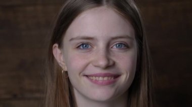 Güzel mutlu bir kızın portresi. Sarı saçlı ve çilli. Kameraya bakıyor ve büyüleyici bir şekilde gülümsüyor.