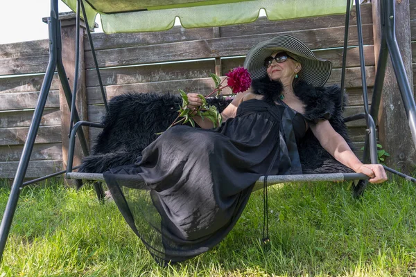 Yaşlarında Saman Şapkalı Mutlu Bir Kadının Portresi Bahçede Salıncakta Dinleniyor — Stok fotoğraf