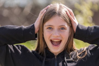 Güzel mutlu bir kızın portresi. Sarı saçlı ve çilli. Kameraya bakıyor ve büyüleyici bir şekilde gülümsüyor.