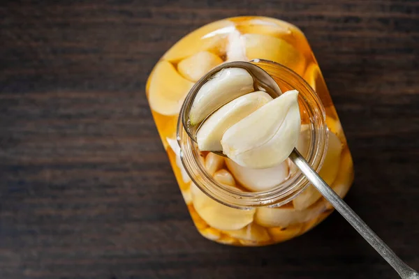 Κουτάλι Φέτες Σκελίδες Σκόρδο Στο Μέλι Πάνω Από Ανοιγμένο Βάζο — Φωτογραφία Αρχείου