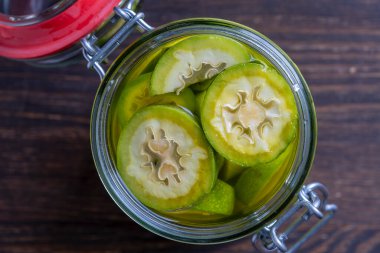 Dilimlenmemiş cevizleri bir kavanozda alkolle, ev yapımı tentür hazırlamak için, yakın çekim. Ahşap bir masada cam bir kavanozda yeşil ceviz tentürü.