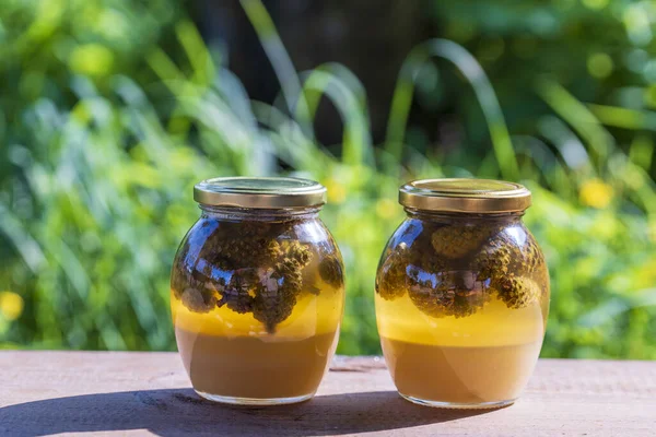 Twee Glazen Potten Verse Honing Met Dennenappels Een Houten Tafel — Stockfoto