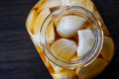 Açılmış bal kavanozunun üzerinde dilimlenmiş sarımsaklı karanfil, üst görünüm, yakın çekim, kopyalama alanı. Ballı sarımsak.