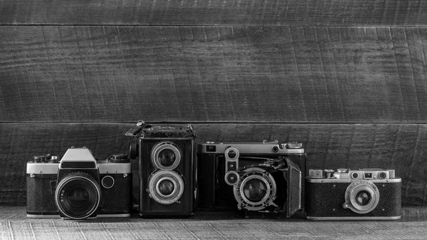 Set of vintage film camera from the times of the USSR on a wooden background, close up, copy space. Line of old retro cameras. Black and white