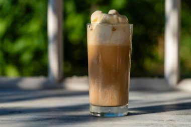 Pencerenin yanındaki pencere eşiğinde dondurmalı bir bardak kahve. Soğuk yaz içkisi. Kapat.