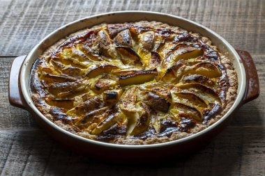 Elmalı turta, ahşap bir masada seramik bir fırın kabında. Ev yapımı elmalı turta. Kapat.
