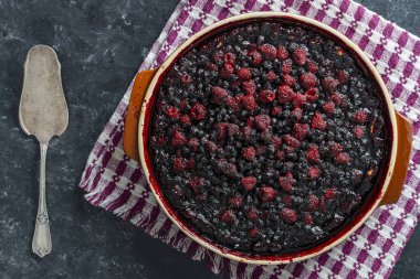 Siyah arka planda seramik bir kasede yabanmersinli ve ahudududulu turta.