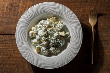 Ekşi kremalı patates salatası ve ahşap arka planda beyaz bir tabakta dereotu.