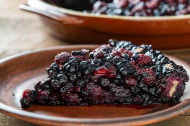 Bir dilim taze yaban mersini ve ahudududulu turta masaya seramik bir tabakta.