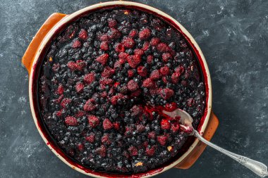 Siyah zemin üzerinde seramik bir tabakta yabanmersinli ve ahudududulu turta.