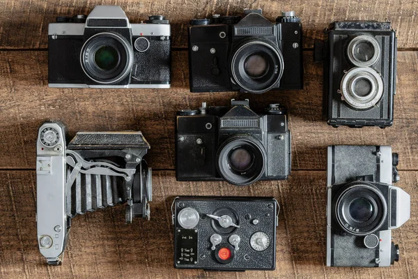 Set of vintage film camera from the times of the USSR on a wooden background, close up, top view. Line of old retro cameras