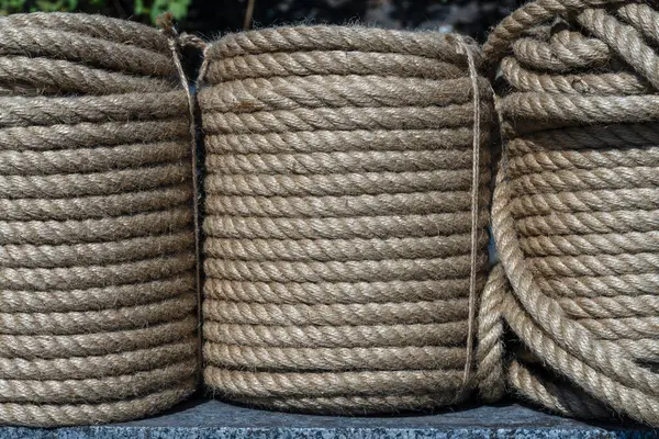 Natural jute hemp rope rolled into a coil, close up. Brown spool of linen rope texture on the background