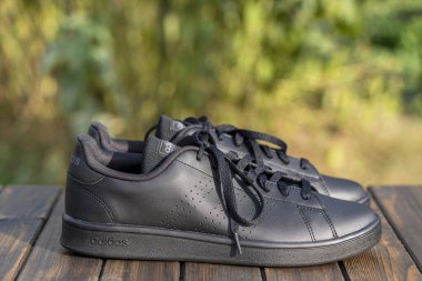 Kyiv, Ukrayna - 05 Ekim 2023: Güzel yeni Adidas tam siyah ayakkabılar ahşap masada, kapat