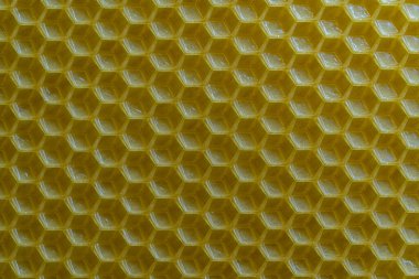 Bal dolu bir arı kovanından alınan balmumu bal peteğinin arka plan dokusu ve şablonu. Voshchina bal peteği yapımında yapay bir temel, hücrelerin balmumu tabakası