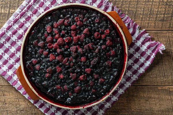 Ahşap zemin üzerinde seramik bir tabakta yabanmersini ve ahududu turtası, yakın plan, üst manzara