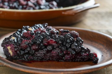 Bir dilim taze yaban mersini ve ahudududulu turta masaya seramik bir tabakta.