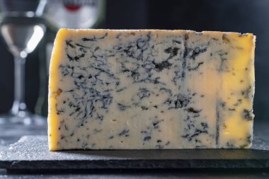 Koyu arkaplanda bir parça mavi peynir, yakın plan.