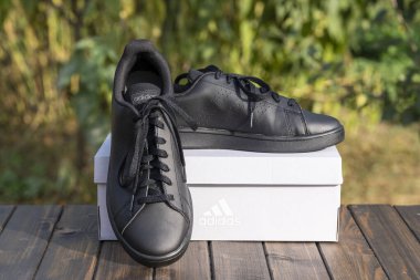 Kyiv, Ukrayna - 05 Ekim 2023: Güzel yeni Adidas tam siyah ayakkabılar ahşap masada, kapat