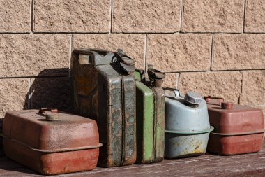 Garajın yakınındaki bir masada paslı demir yakıt bidonları var. Yaklaş. Benzin için çeşitli metal kaplar, retro tarzı.