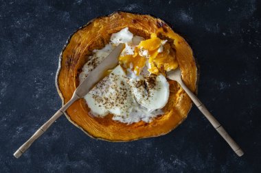 Yarım pişmiş balkabağı ve koyu arkaplanda sahanda yumurta, üst manzara, yakın çekim.