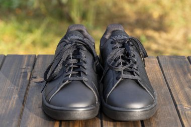 Kyiv, Ukrayna - 05 Ekim 2023: Güzel yeni Adidas tam siyah ayakkabılar ahşap masada, kapat
