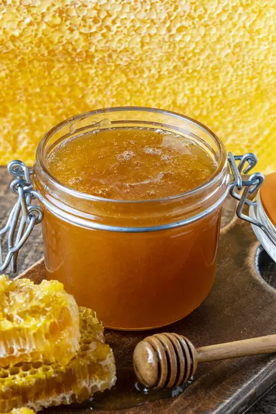 木のスプーンとハニカムが付いている厚い黄金の蜂蜜のガラス瓶 養蜂の概念について 甘い蜂蜜プロダクト 健康な食糧 — ストック写真