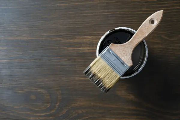 Top view on paint brush on the opened can on the wooden table background or floor painting and renovation repairing concept, copy space