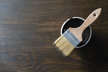 Açılmış konserve kutusundaki boya fırçasının üst görünümü ahşap masa arka planında veya zemin boyama ve yenileme konsepti, kopyalama alanı