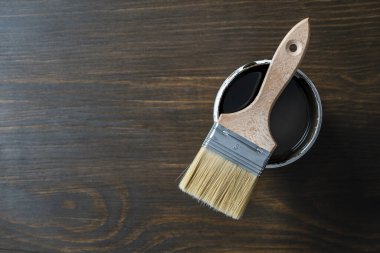 Açılmış konserve kutusundaki boya fırçasının üst görünümü ahşap masa arka planında veya zemin boyama ve yenileme konsepti, kopyalama alanı