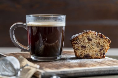 Kırmızı kirazlı enfes kek, ceviz ve tahta bir masanın üzerinde bir bardak koyu kahve, yakın çekim. Kahvaltıda taze kek ve kahve.
