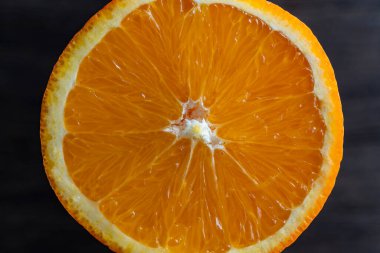 Dilimlenmiş olgun portakalı kapat, makro. Ahşap arka planda sarı turuncu yüzey. Üst görünüm