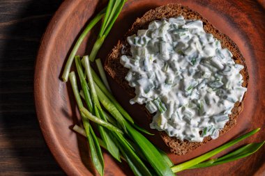 Ekmekli lezzetli sandviç, yeşil yabani sarımsak salatası ve tabakta ekşi krema, kapat.