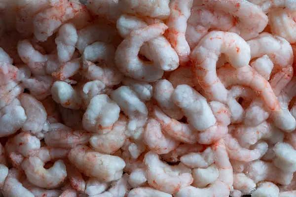 Lots of frozen shrimp for background use, close up, top view. Seafood on the counter. Fish market. Peeled boiled shrimps