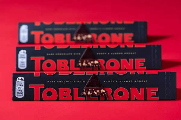 乌克兰基辅 2024年3月20日 多夫隆瑞士黑巧克力与蜂蜜和杏仁努加酒红色背景 Toblerone是Mondelez International的瑞士巧克力吧 图库照片